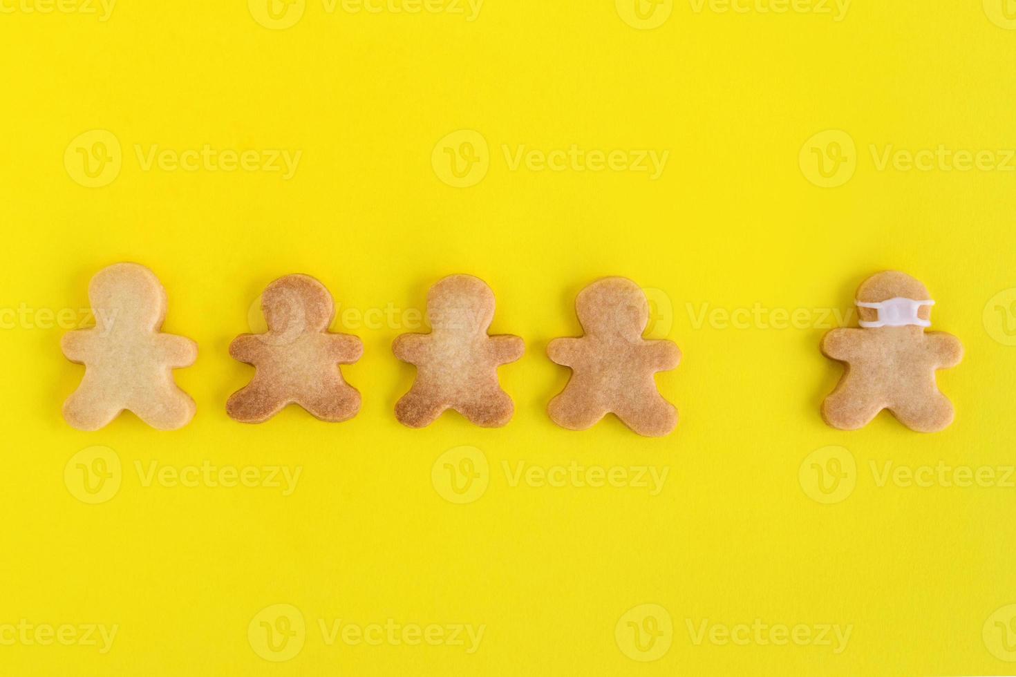 Homemade shortbread cookies with white glaze on yellow background, top view. Crowd of people and one man in face mask. photo