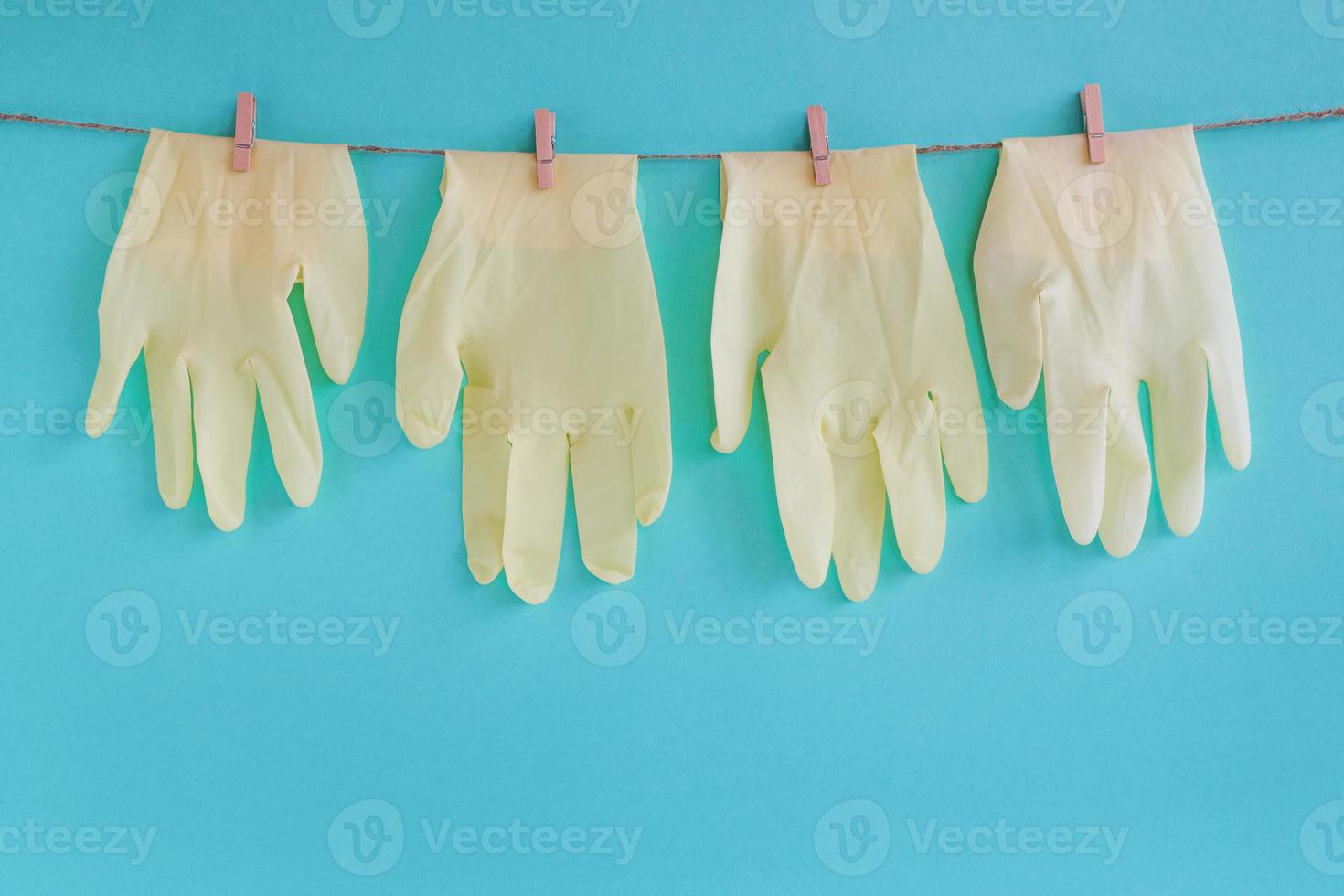 Drying of disposable medical gloves after washing on a rope for reuse, on a turquoise background. Concept of new normal lifestyle. photo
