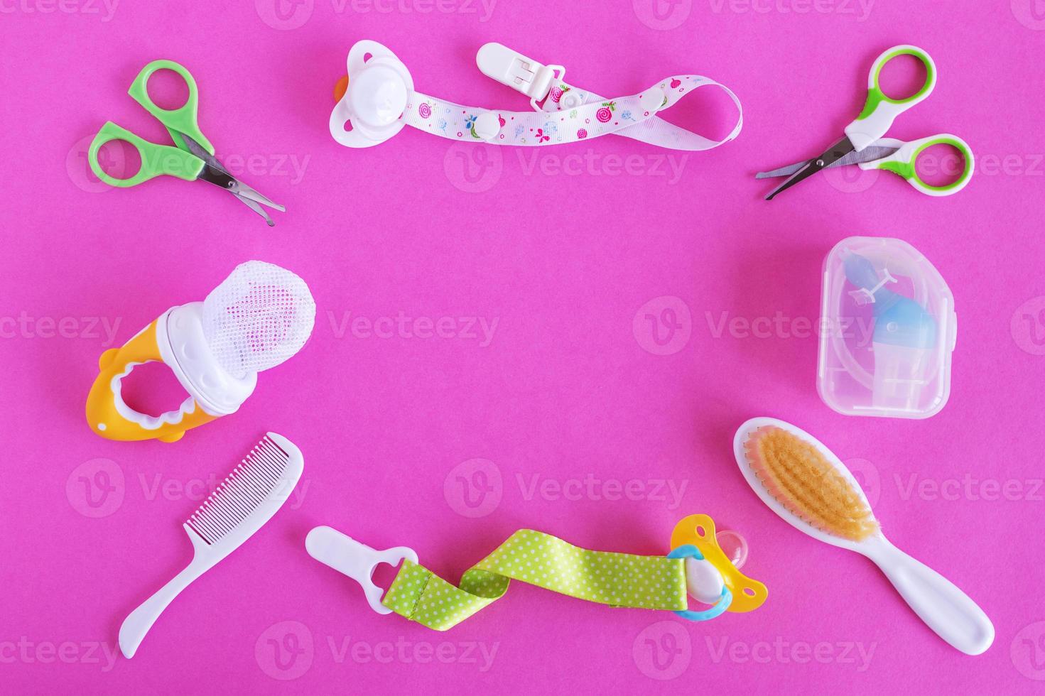 Flat lay on baby care items - scissors, hairbrushes, pacifiers, pacifier holders, nasal aspirator and nibbler- on pink background with copy space. Concept of medicine and hygiene of the child. photo