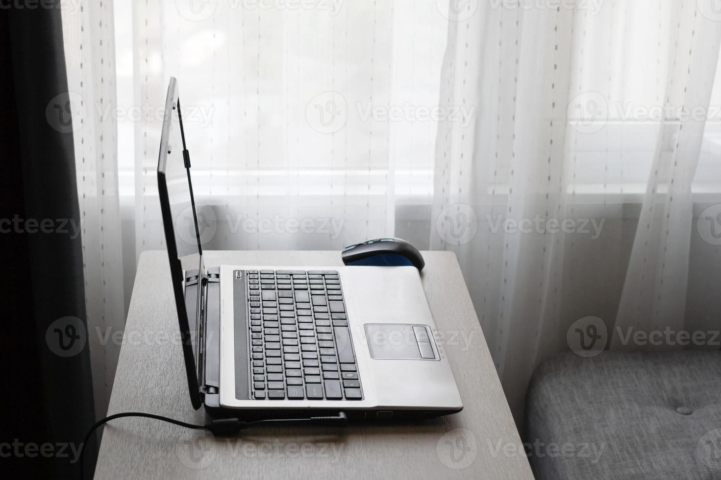 Work from home on the table with laptop and gray sofa near to window. photo