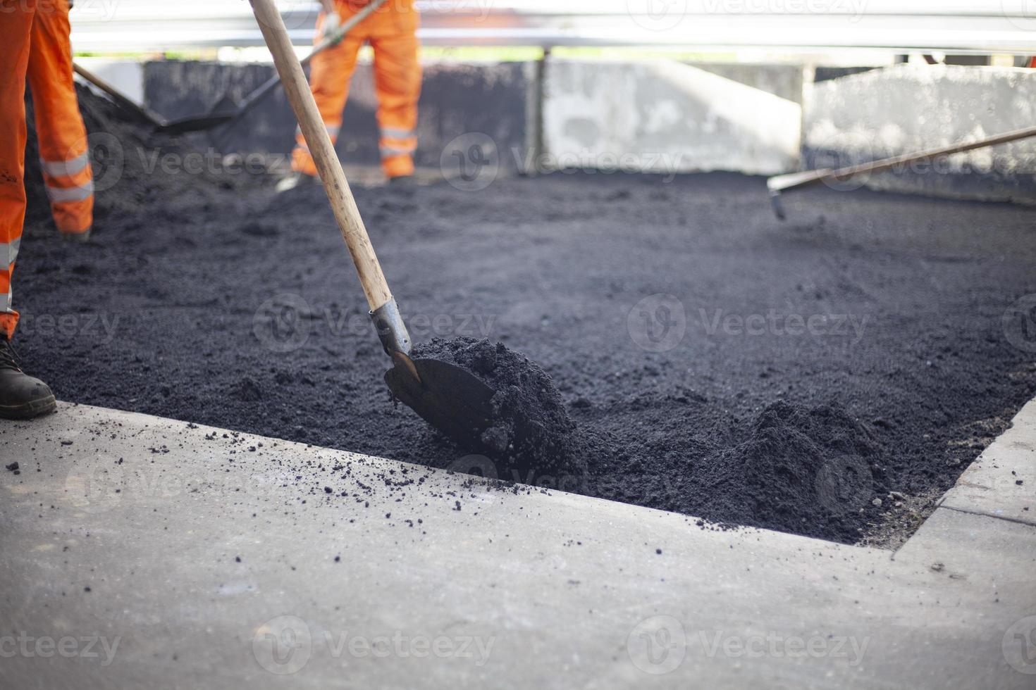 Worker lays asphalt. Repair of road. Create surface. Repair work in city. photo