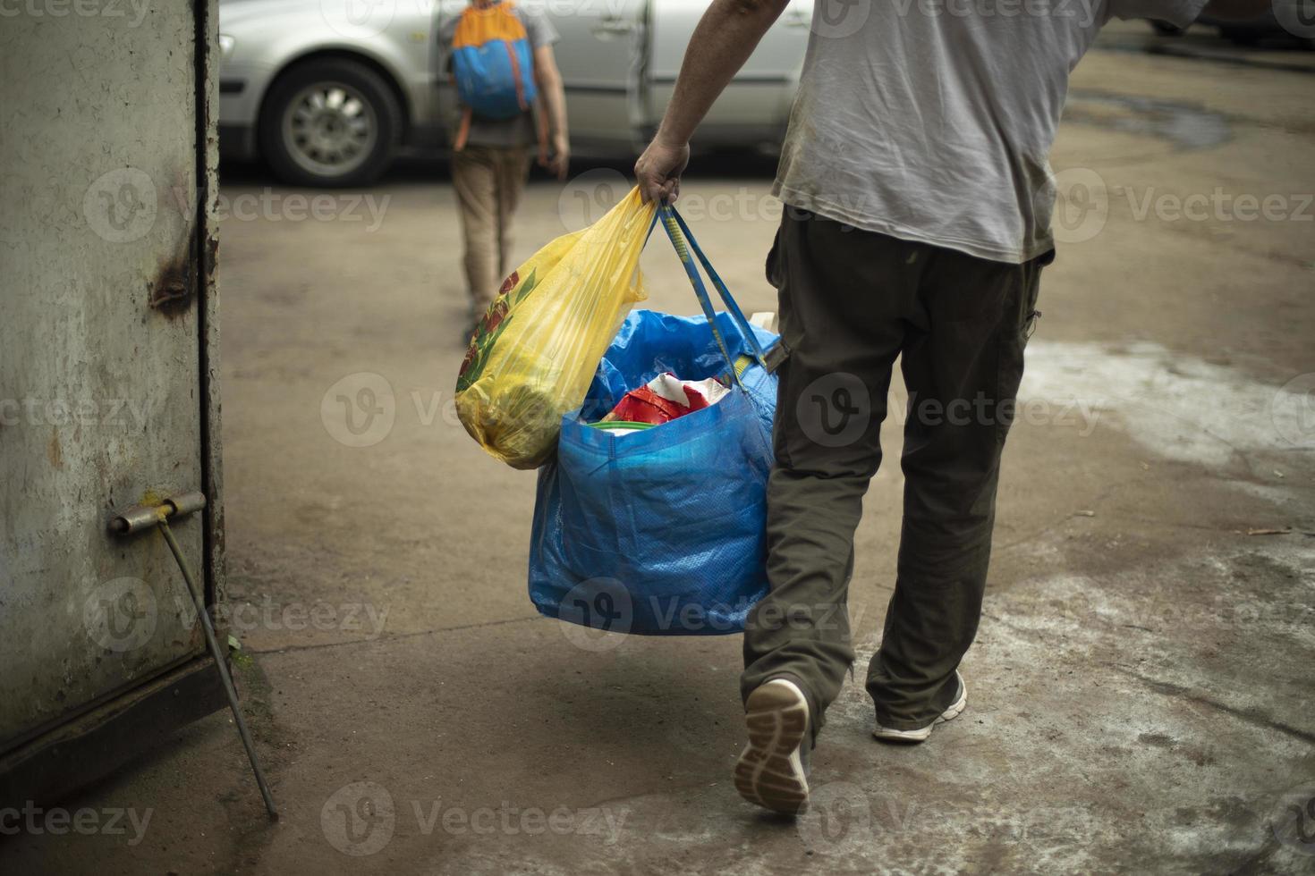 Man carrying blue bag. Moving with things. Guy dragging things. photo