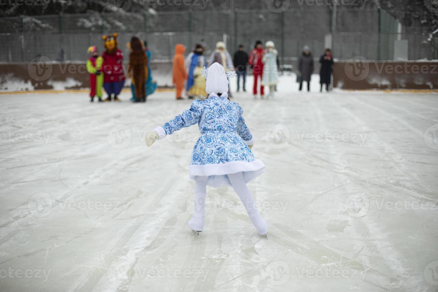 Child on skates. Ice rink in winter. Active lifestyle in winter. Girl is engaged in figure skating. photo