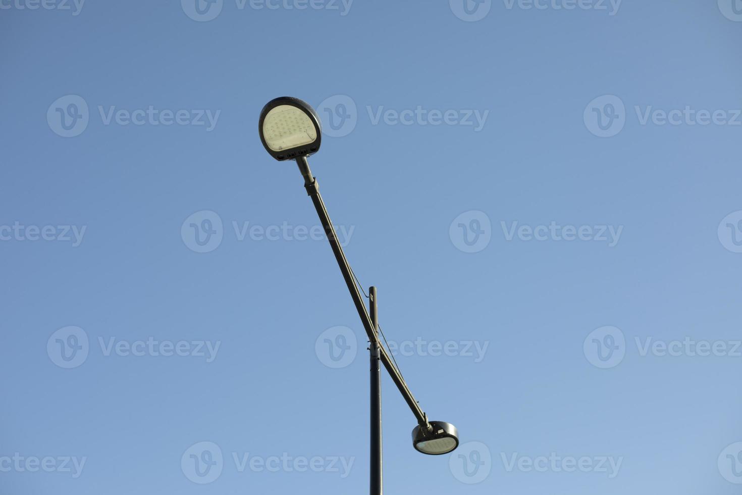 Pole with lamp against sky. Lighting fixture in city. photo