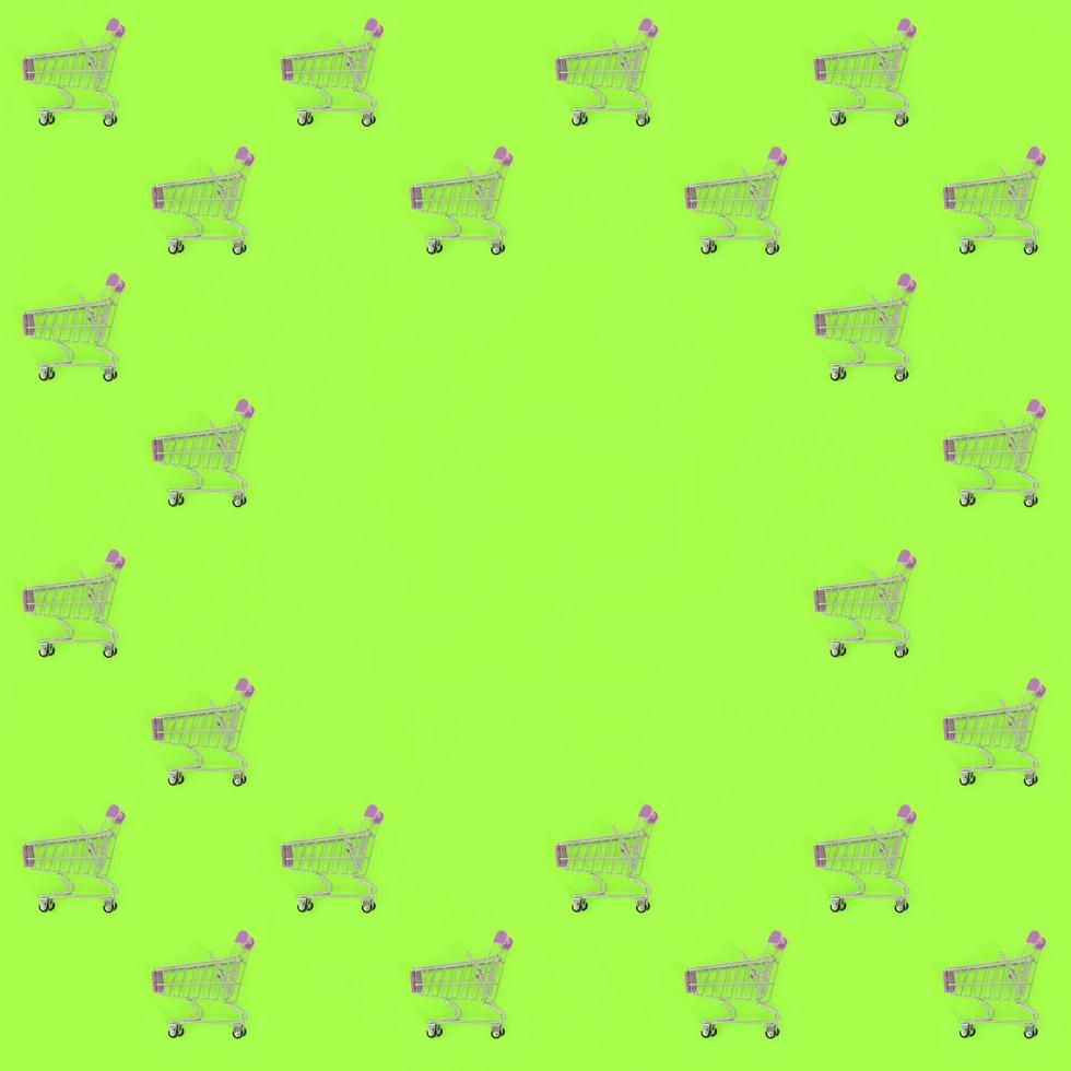 Shopping addiction, shopping lover or shopaholic concept. Many small empty shopping carts perform a pattern on a pastel colored paper background. Flat lay composition, top view photo
