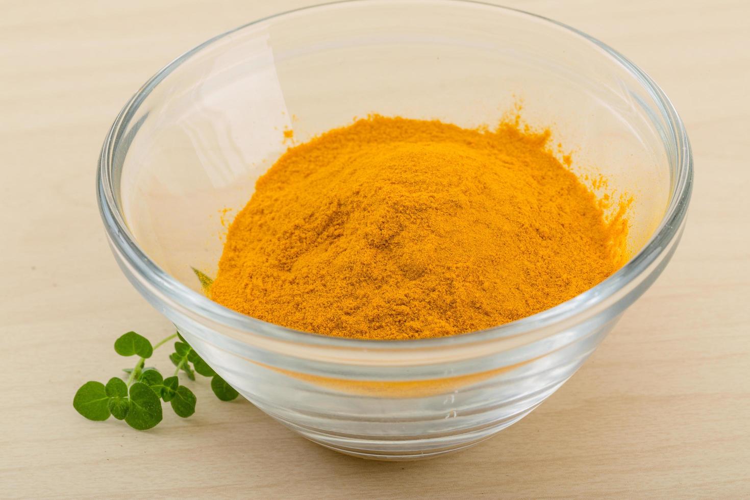 Tumeric powder in a bowl on wooden background photo
