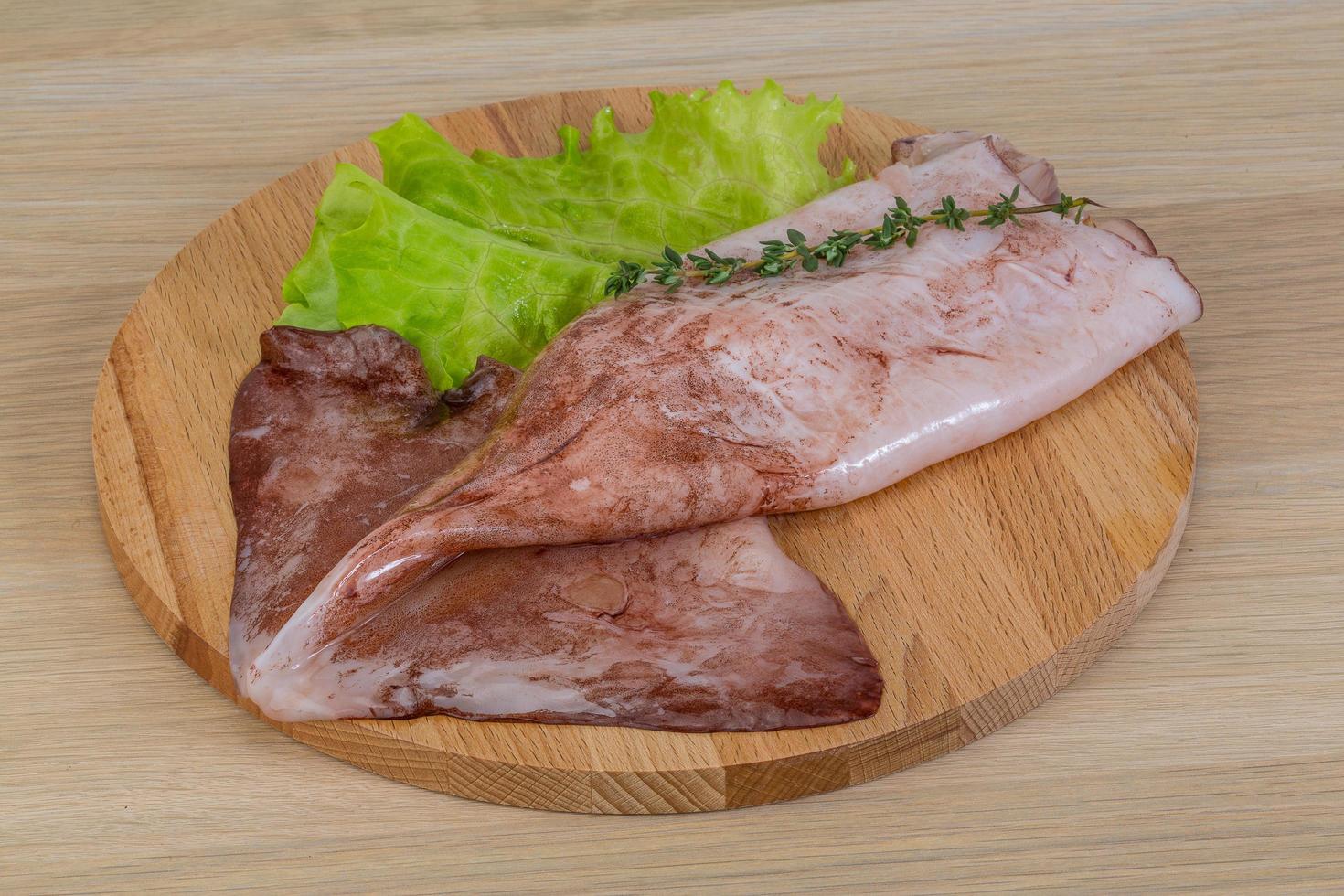 Raw squids on wooden board and wooden background photo