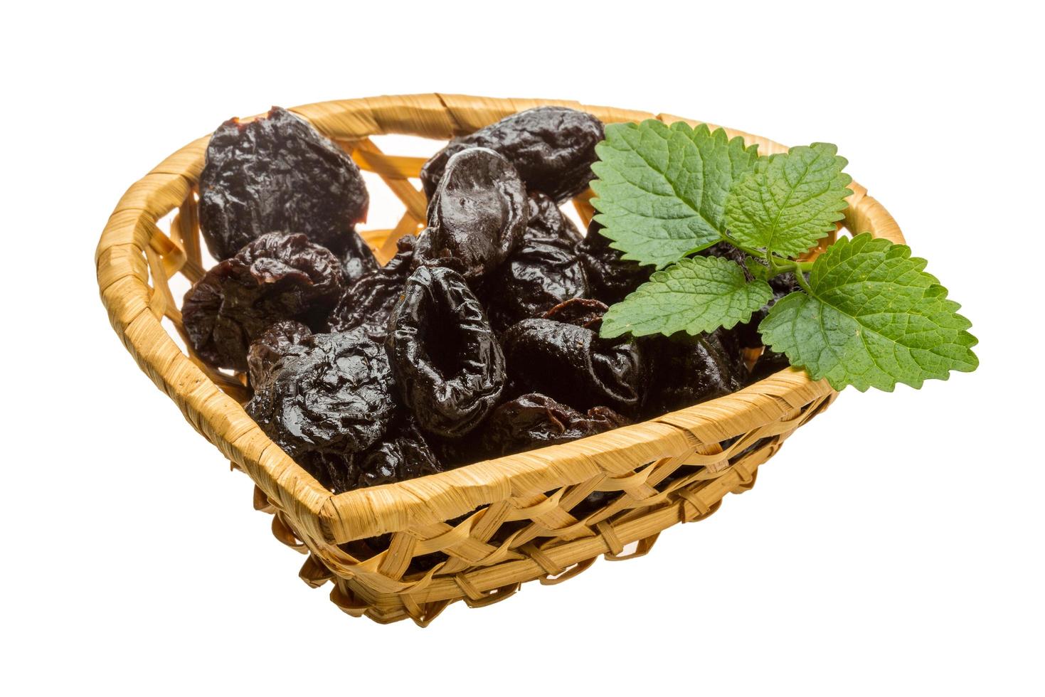 Dried plums in a basket on white background photo