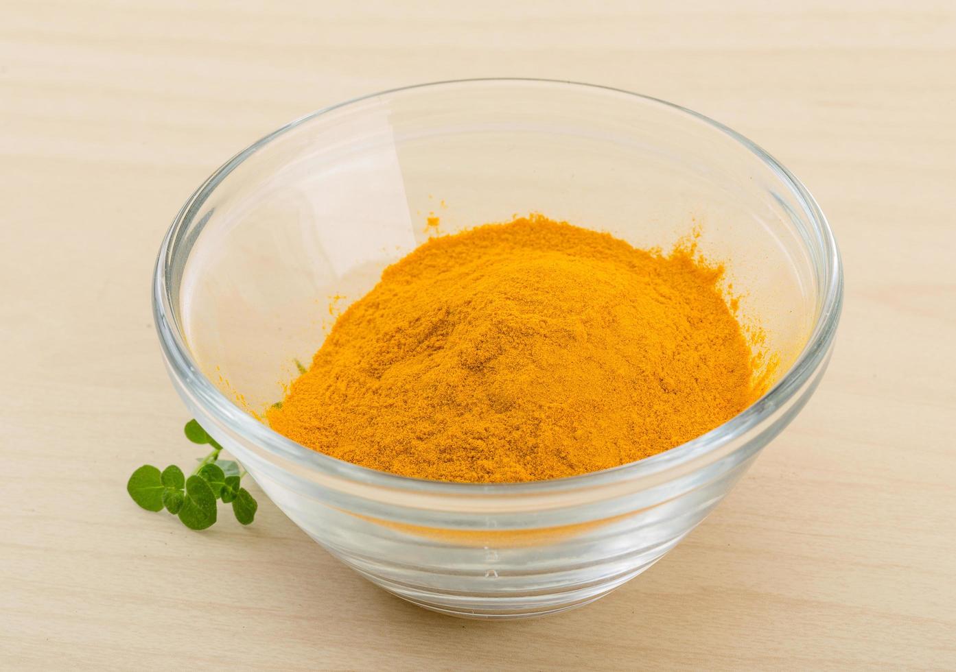 Tumeric powder in a bowl on wooden background photo