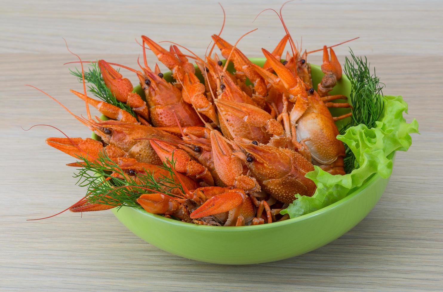 Boiled crayfish in a bowl on wooden background photo