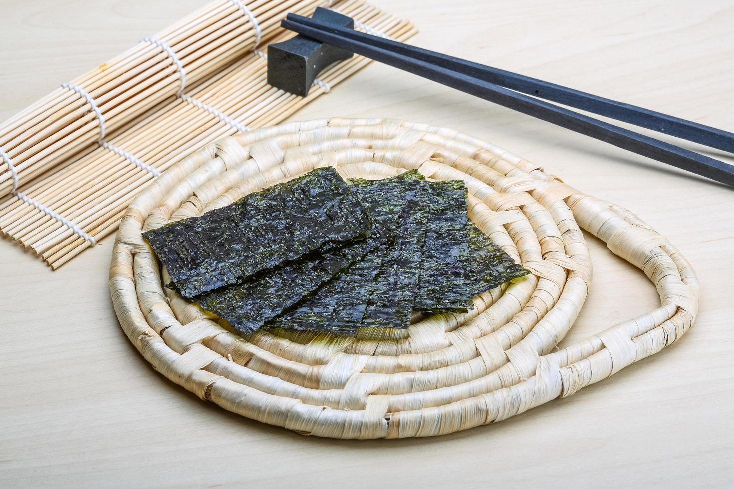 Nori sheets on wooden board and wooden background photo