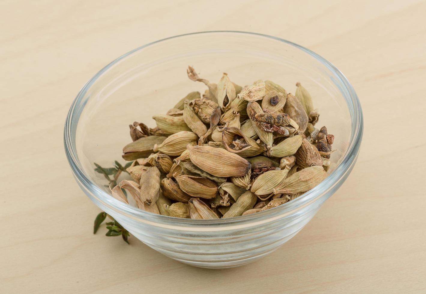 Cardamom in a bowl on wooden background photo