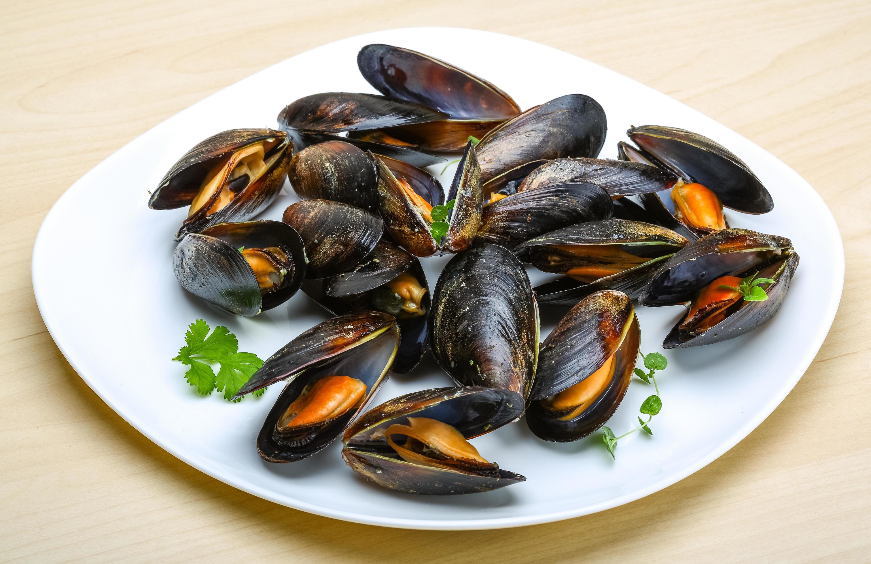 Boiled mussels on the plate and wooden background 12688189 Stock Photo