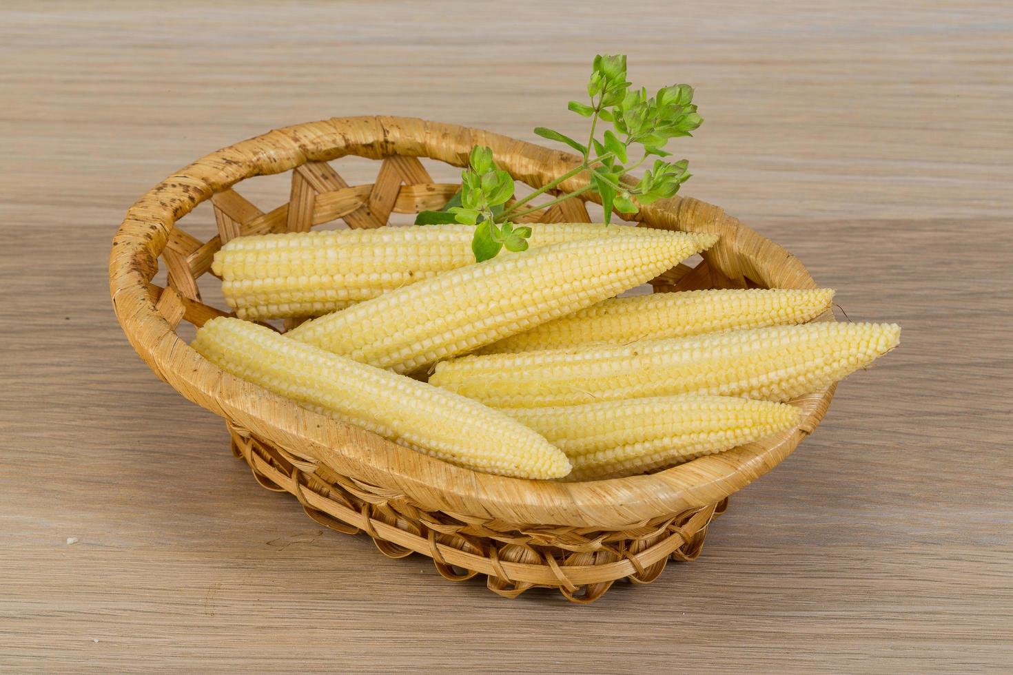 Baby corn in a basket on wooden background photo