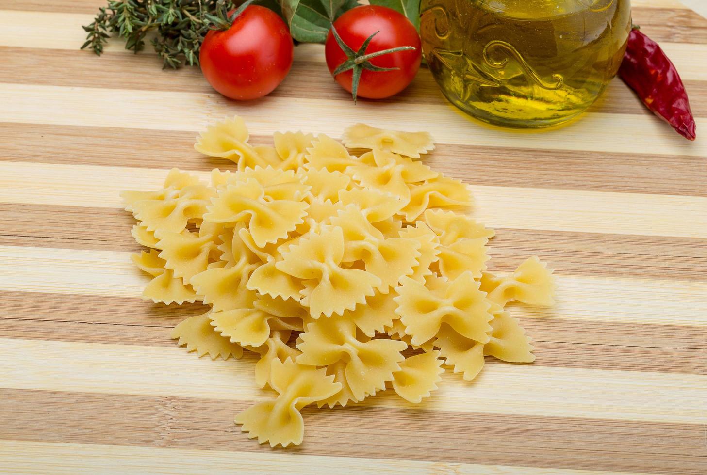 Raw farfalle on wooden board and wooden background photo