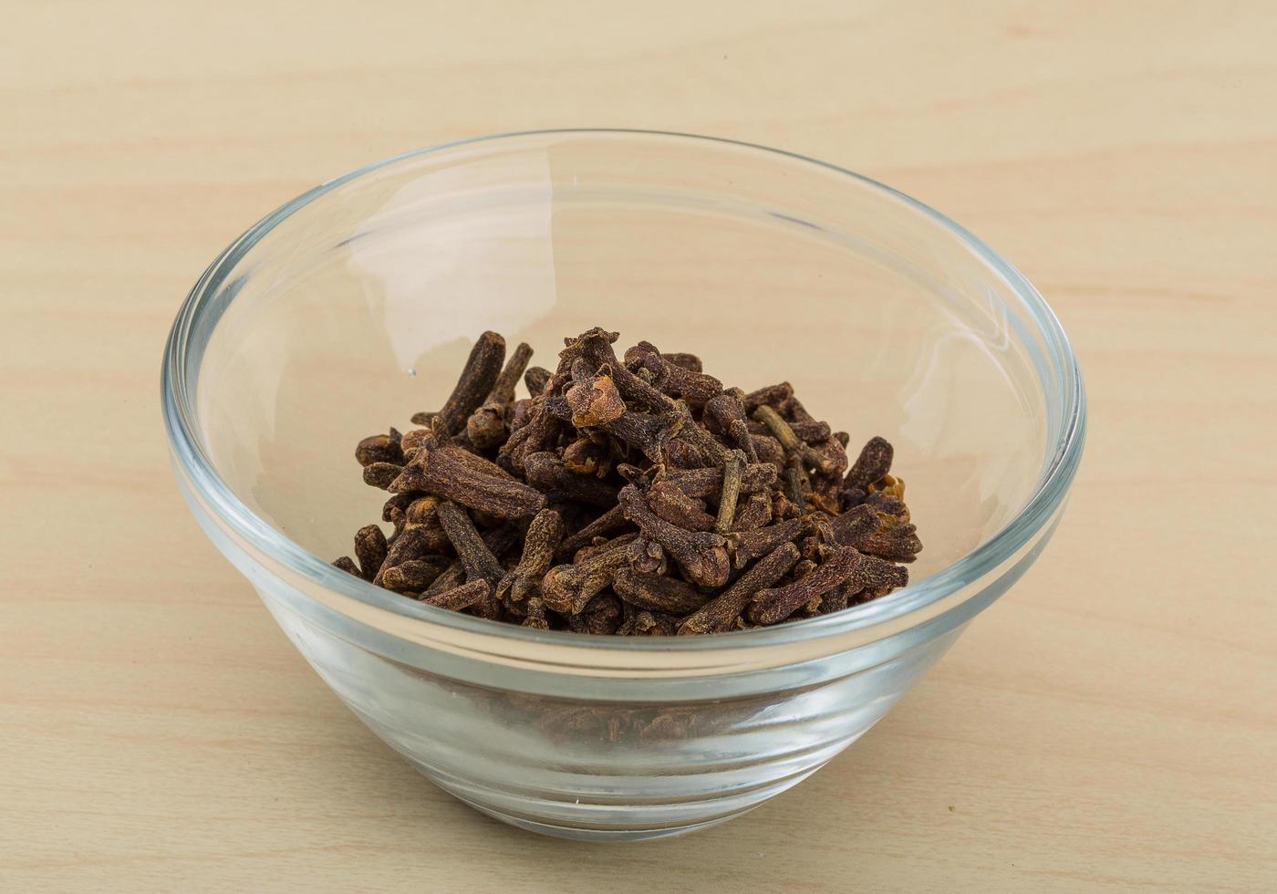 Clove seeds in a bowl on wooden background photo