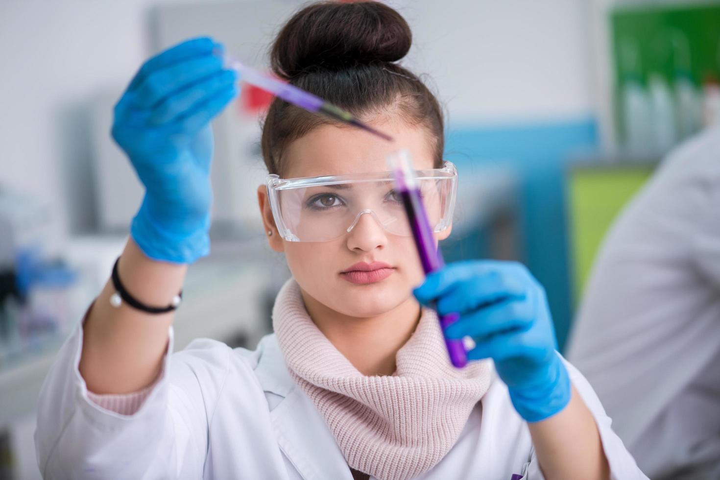 female student with protective glasses making chemistry experiment photo