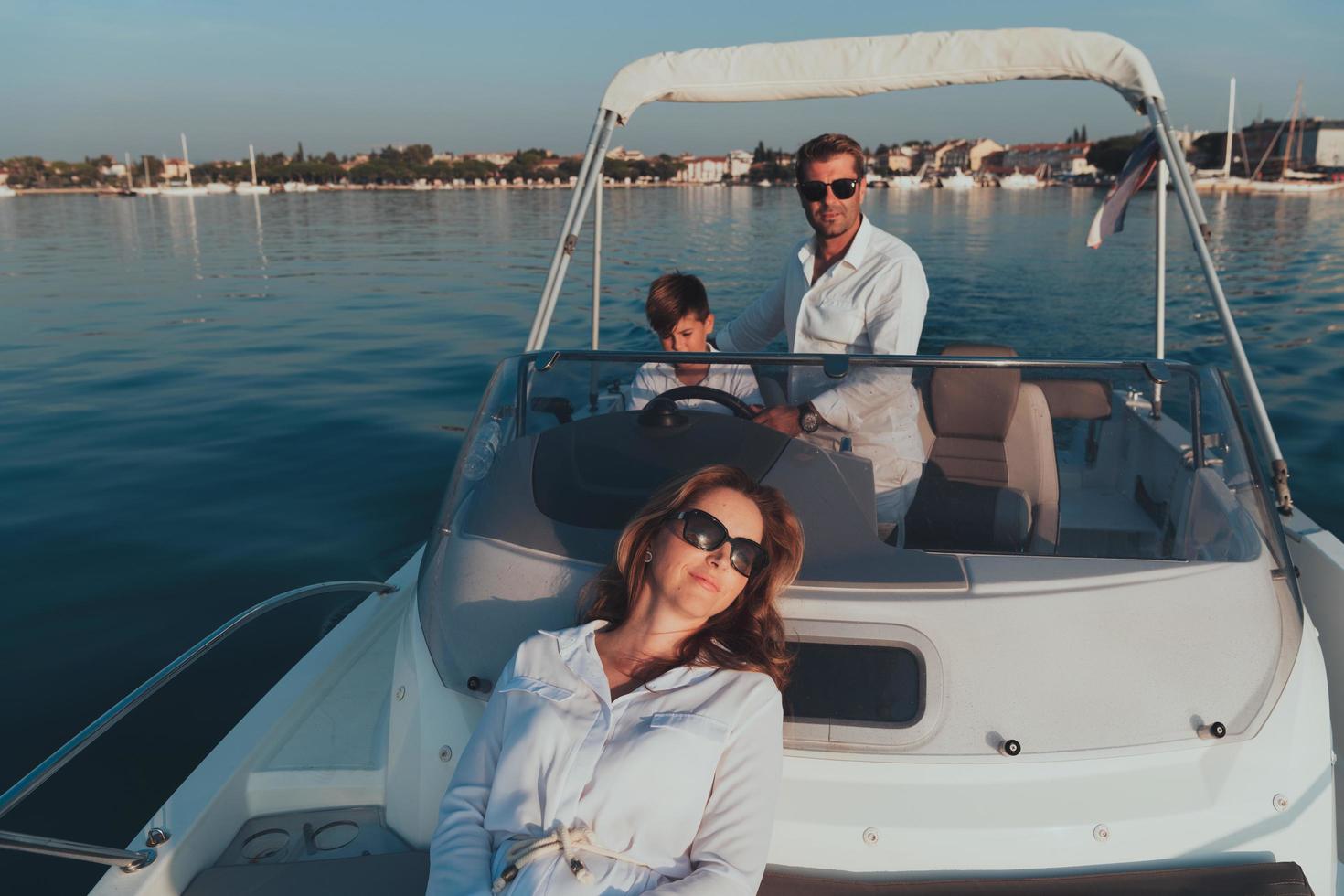 A senior couple in casual outfits with their son enjoy while riding a boat at sea at sunset. The concept of a happy family. Selective focus photo