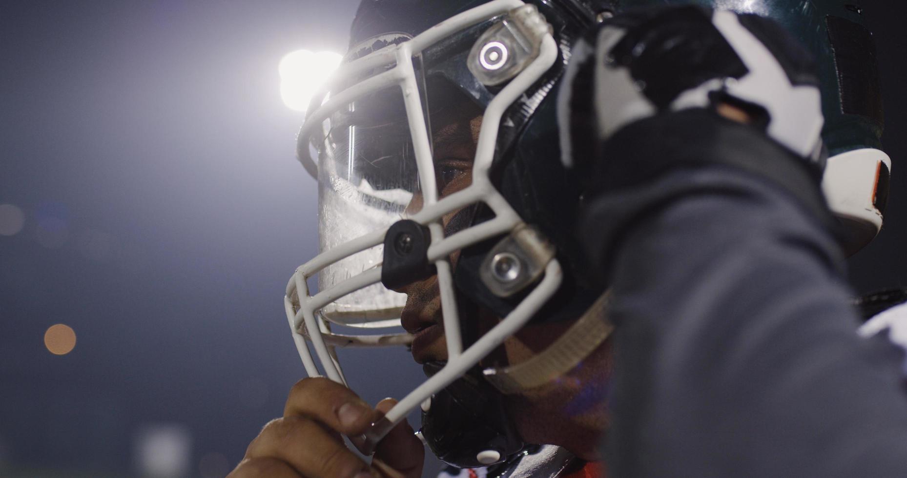 American Football Player Putting On Helmet on large stadium with lights in background photo