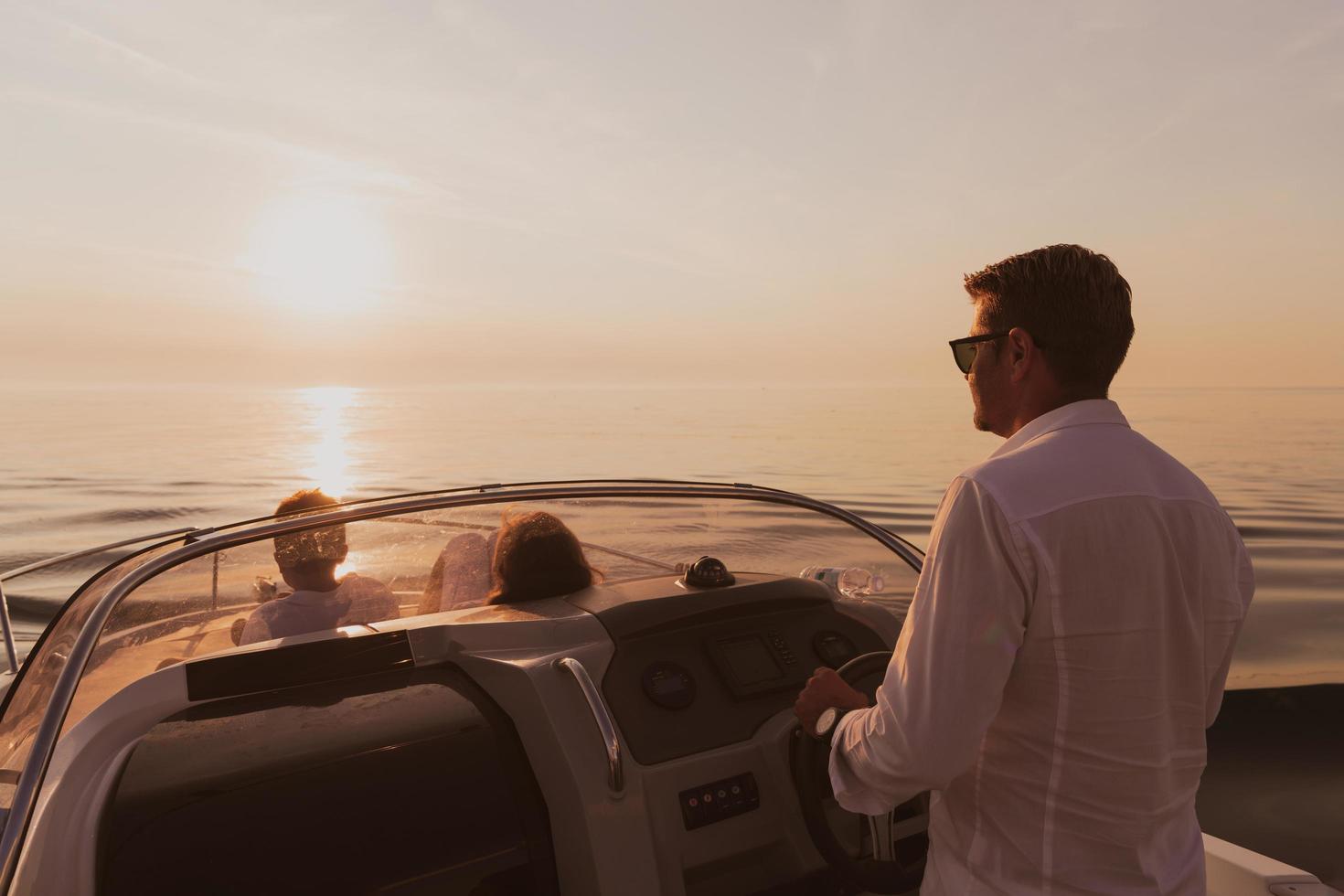 una pareja mayor con ropa informal con su hijo disfruta mientras viaja en un bote en el mar al atardecer. el concepto de una familia feliz. enfoque selectivo foto