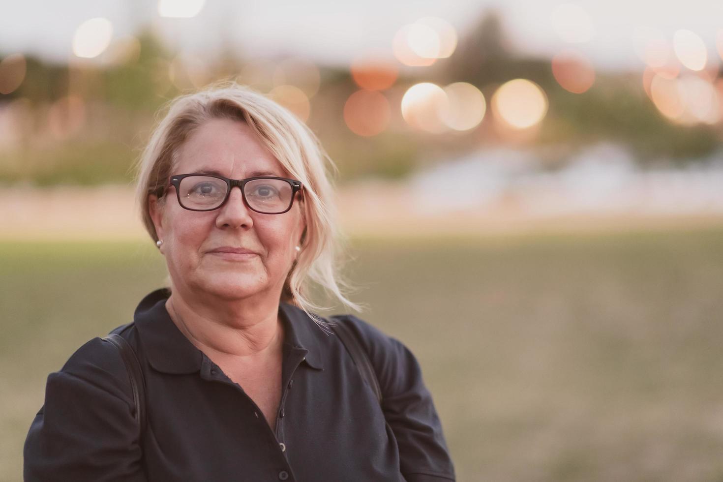 Portrait of an elderly woman with blonde hair and glasses on the beaches of the Mediterranean Sea at sunset. Selective focus photo