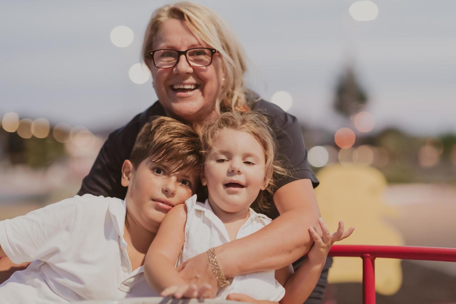 An older grandmother is playing with her grandchildren in a park at sunset. Selective focus photo