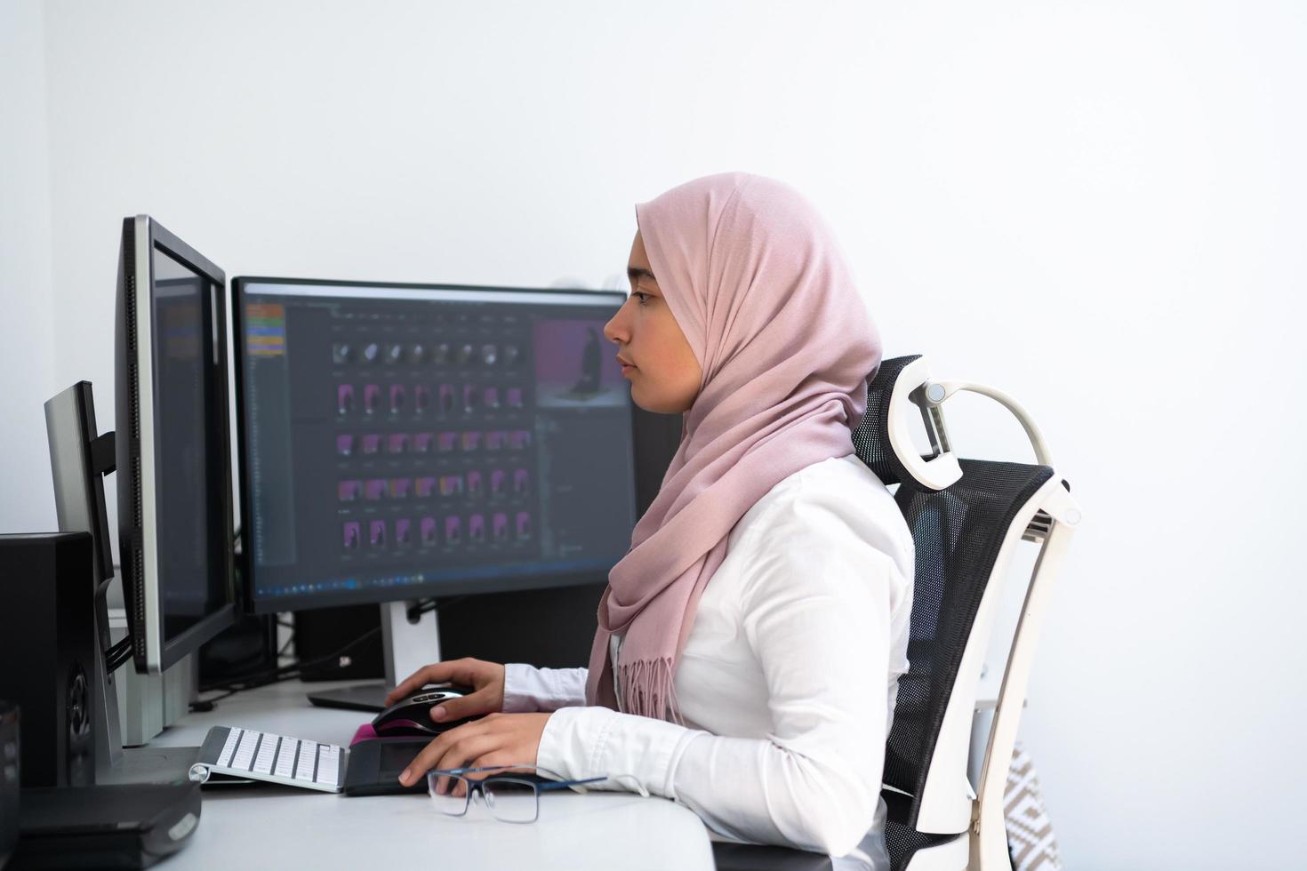 profesional creativa árabe femenina que trabaja en la oficina en casa en una computadora de escritorio con vista superior de monitor de pantalla dual. enfoque selectivo foto