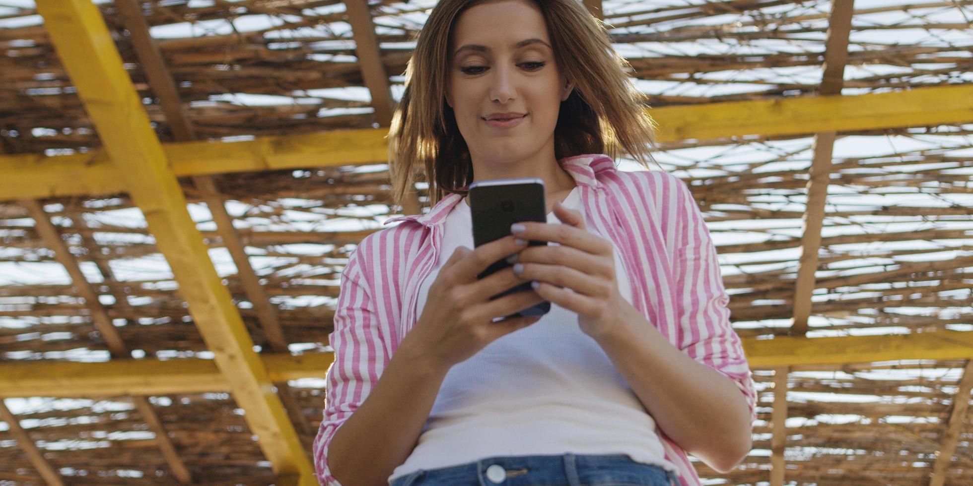 mujer smartphone enviando mensajes de texto por teléfono celular en la playa foto