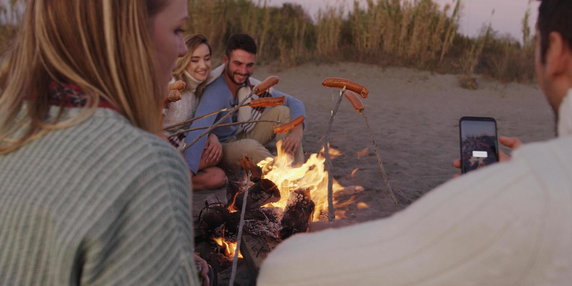 Group Of Young Friends Sitting By The Fire at beach photo