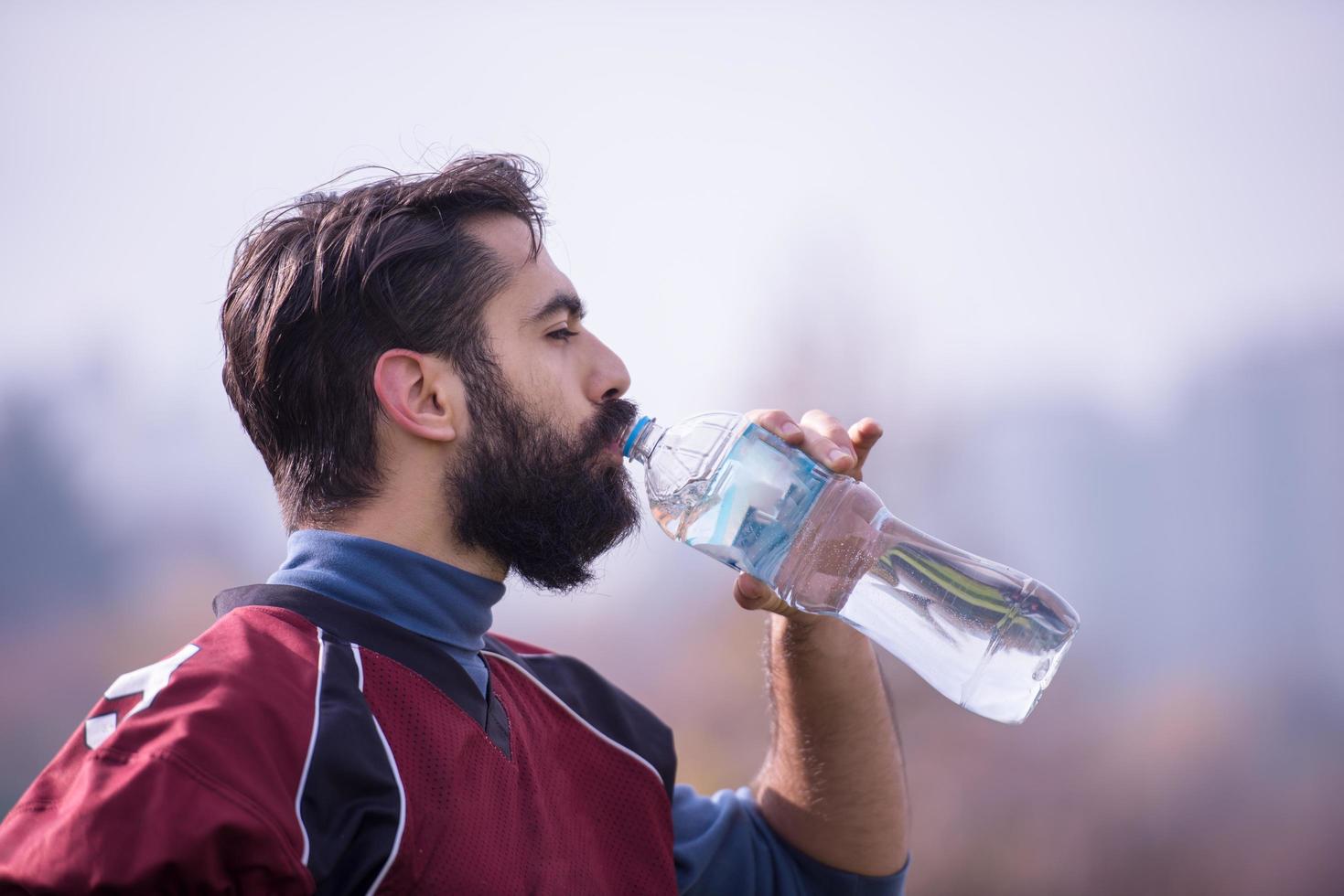 jugador de fútbol americano bebiendo agua después de un duro entrenamiento foto