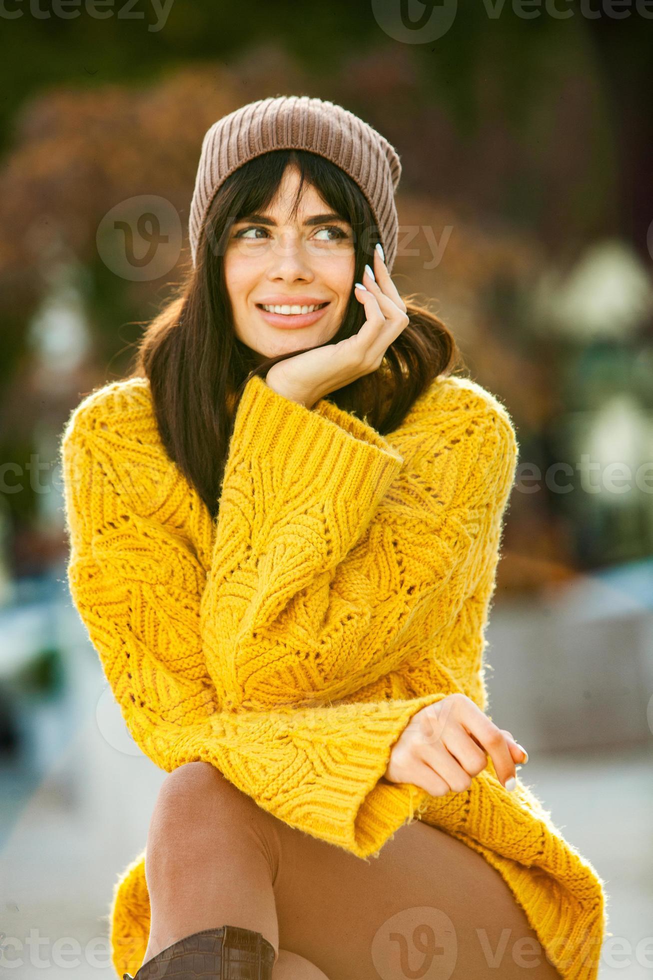 Beautiful European brunette dressed in a yellow woolen sweater and hat  outside. The beautiful girl who wears thick stylish autumn clothes in cool  weather. 12824197 Stock Photo at Vecteezy