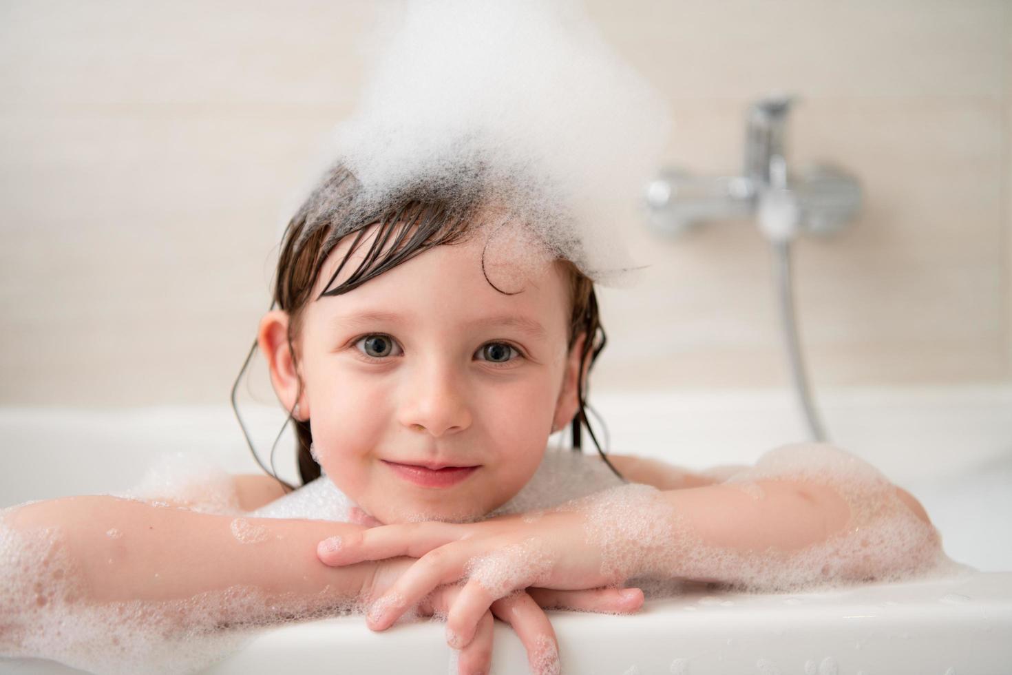 niña en el baño jugando con espuma foto