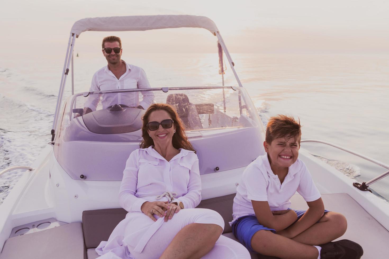 A senior couple in casual outfits with their son enjoy while riding a boat at sea at sunset. The concept of a happy family. Selective focus photo
