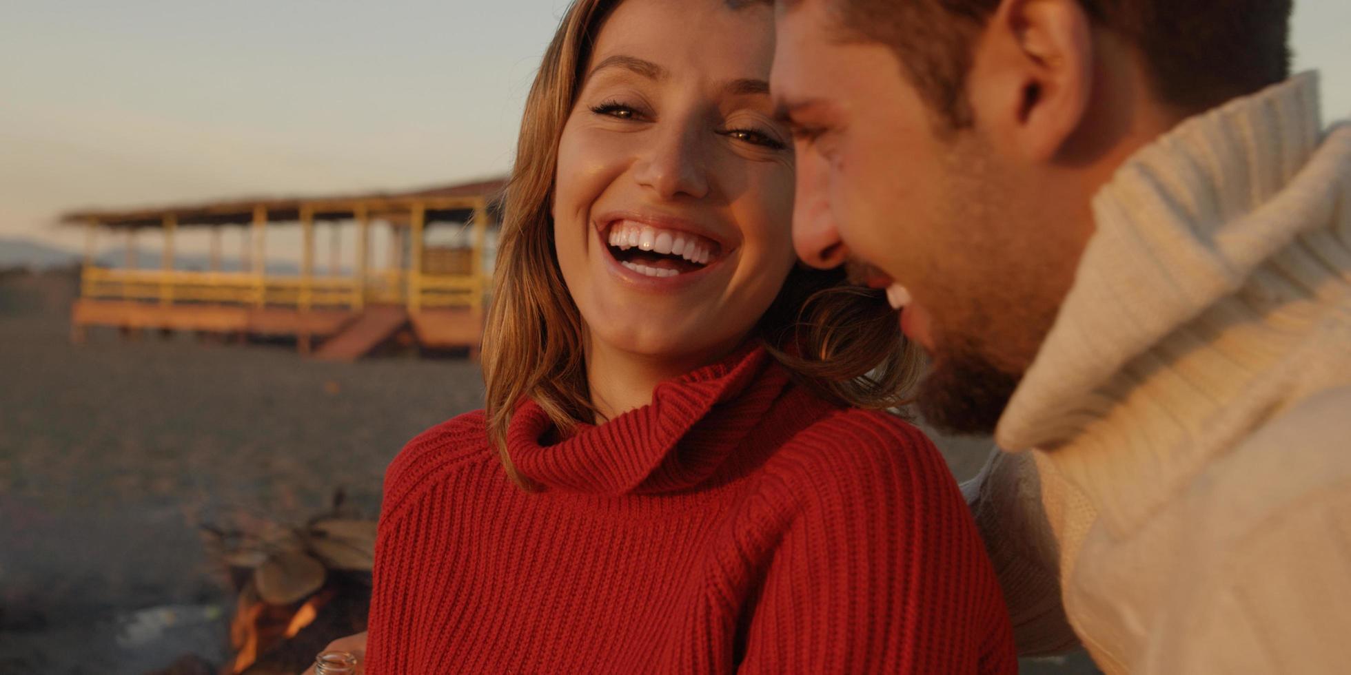 Loving Young Couple Sitting On The Beach beside Campfire drinking beer photo