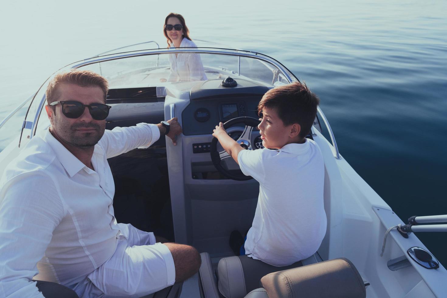 A senior couple in casual outfits with their son enjoy while riding a boat at sea at sunset. The concept of a happy family. Selective focus photo