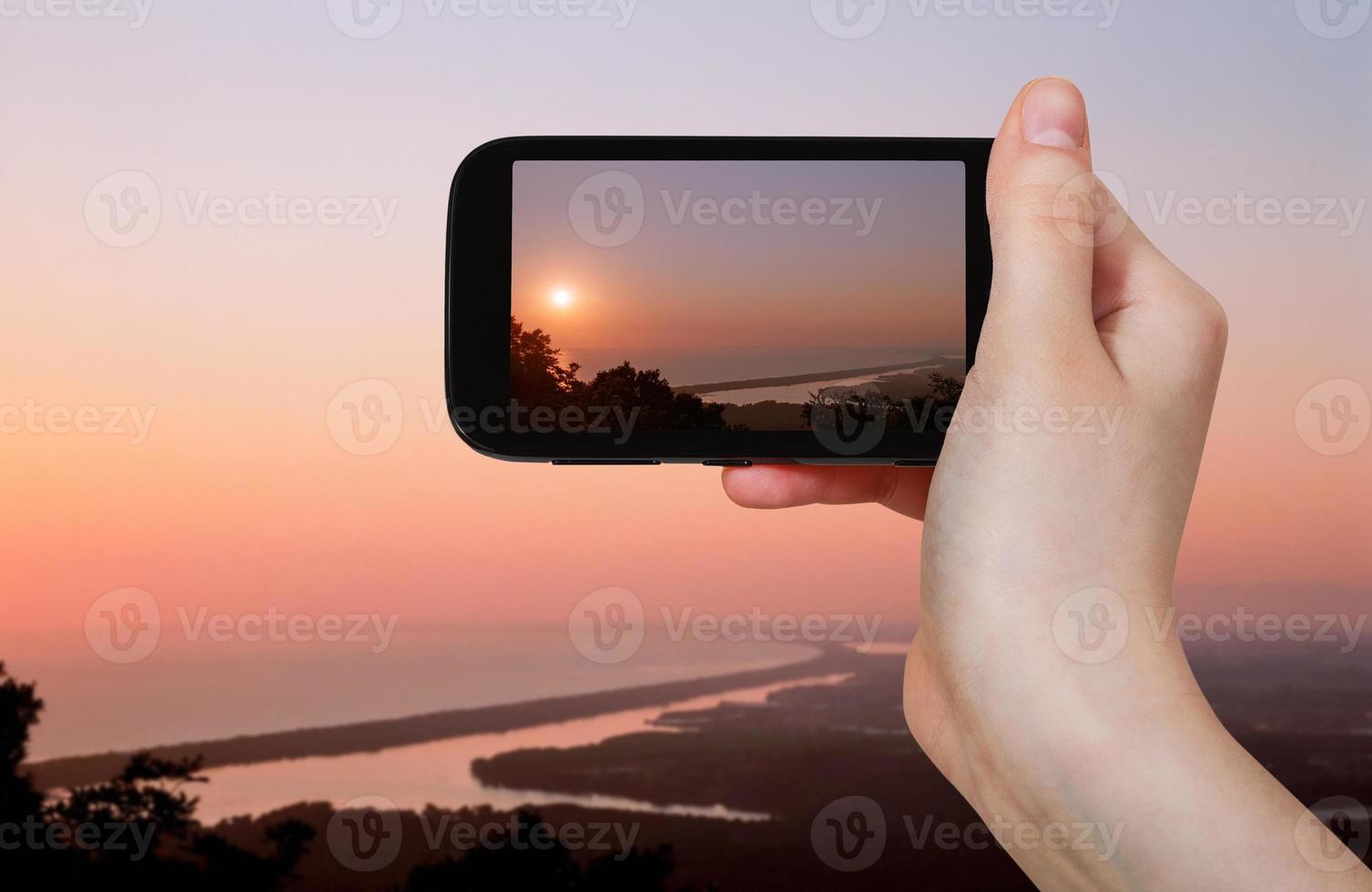 turista tomando fotos del lago salado al atardecer rosa