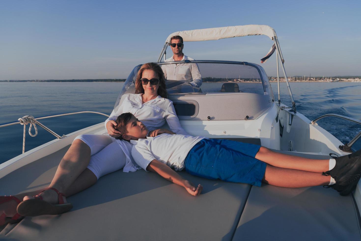 una pareja mayor con ropa informal con su hijo disfruta mientras viaja en un bote en el mar al atardecer. el concepto de una familia feliz. enfoque selectivo foto