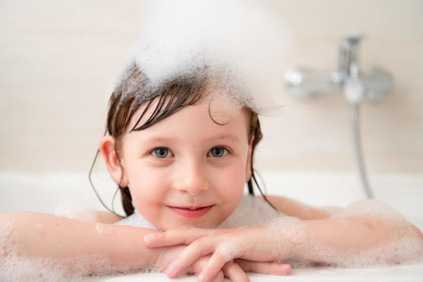 little girl in bath playing with foam photo