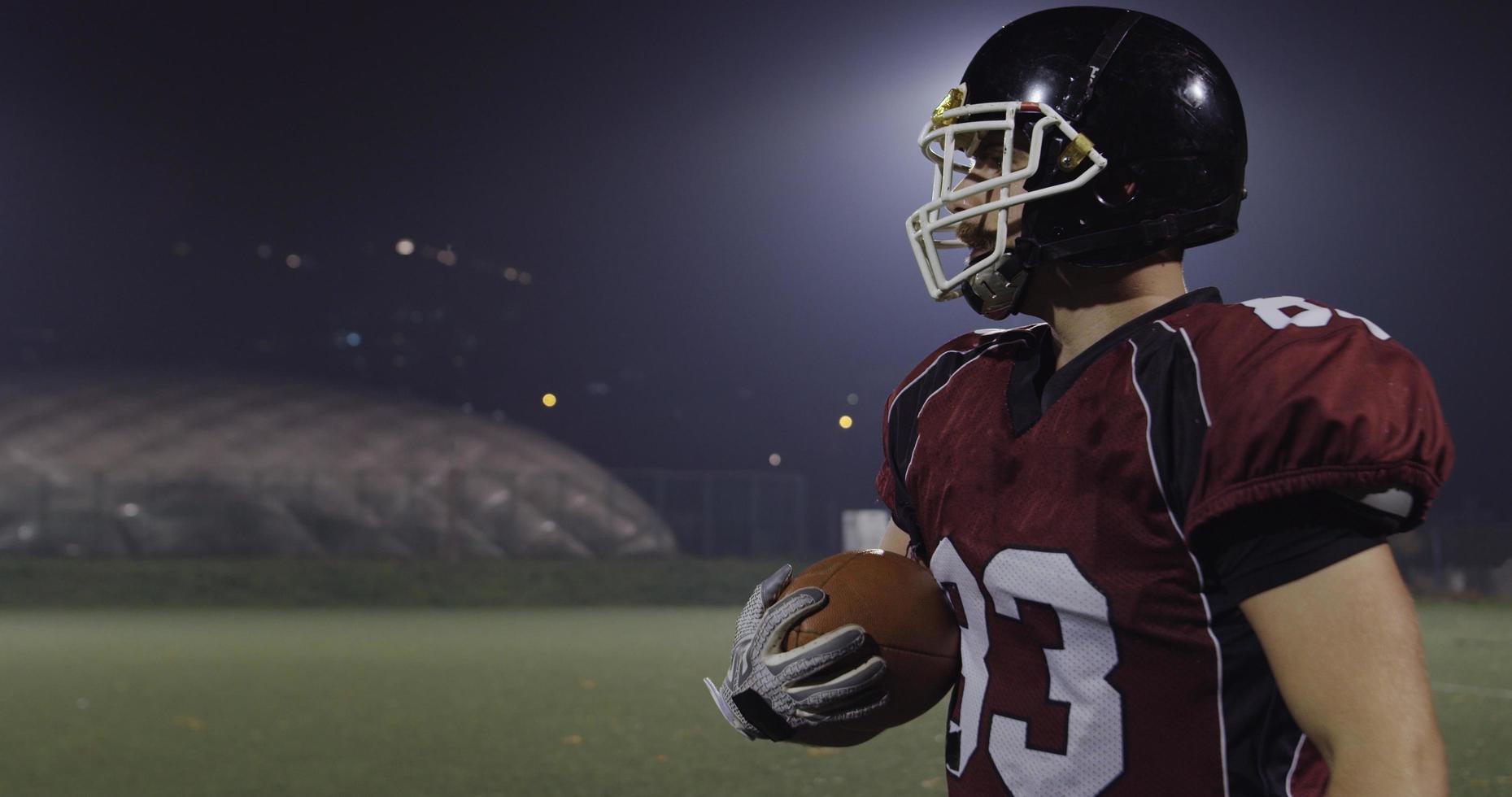 American football player holding ball while running on field photo