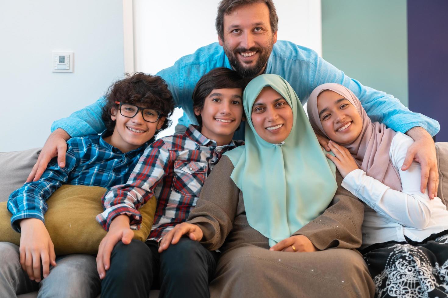 Portrait photo of an arab muslim family sitting on a couch in the living room of a large modern house. Selective focus