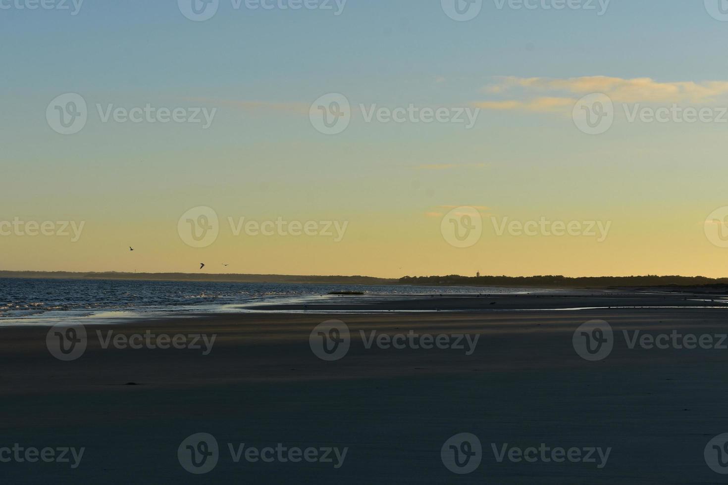 Beautiful sunset in cape cod with a light house in the distance photo