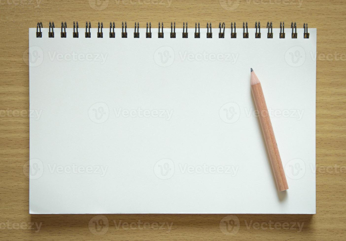 blank spiral notepad and pencil on wood background photo