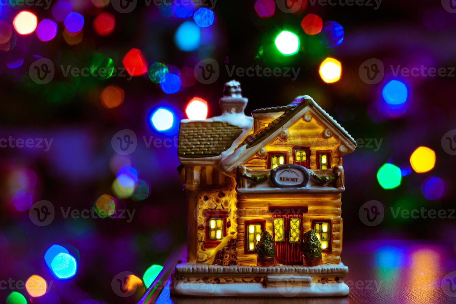 figura de la casa de navidad en la mesa sobre fondo multicolor borroso foto