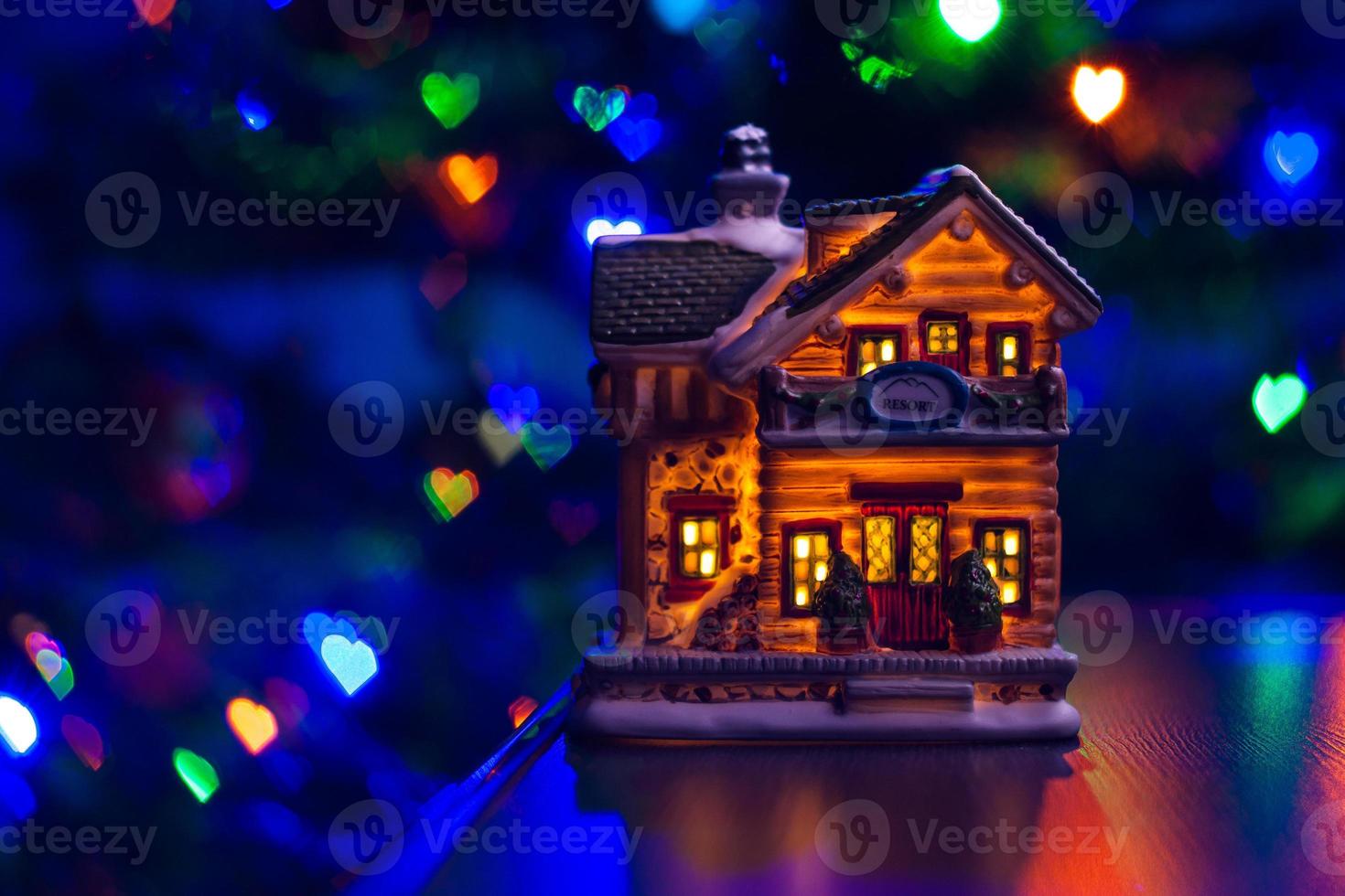 figura de la casa de navidad en la mesa sobre fondo de bokeh de corazón borroso multicolor foto