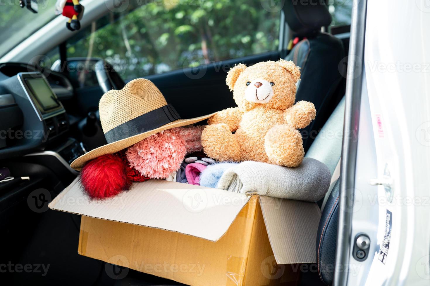 Volunteer woman provide clothing donation box with used clothes and doll at home to support help for refugee, homeless or poor people in the world. photo