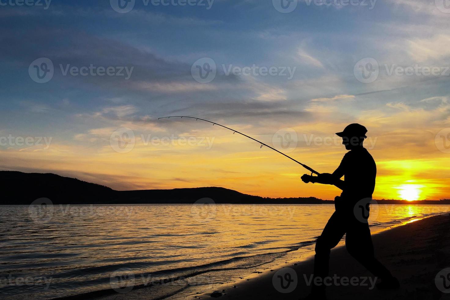 Young man fishing at sunset photo