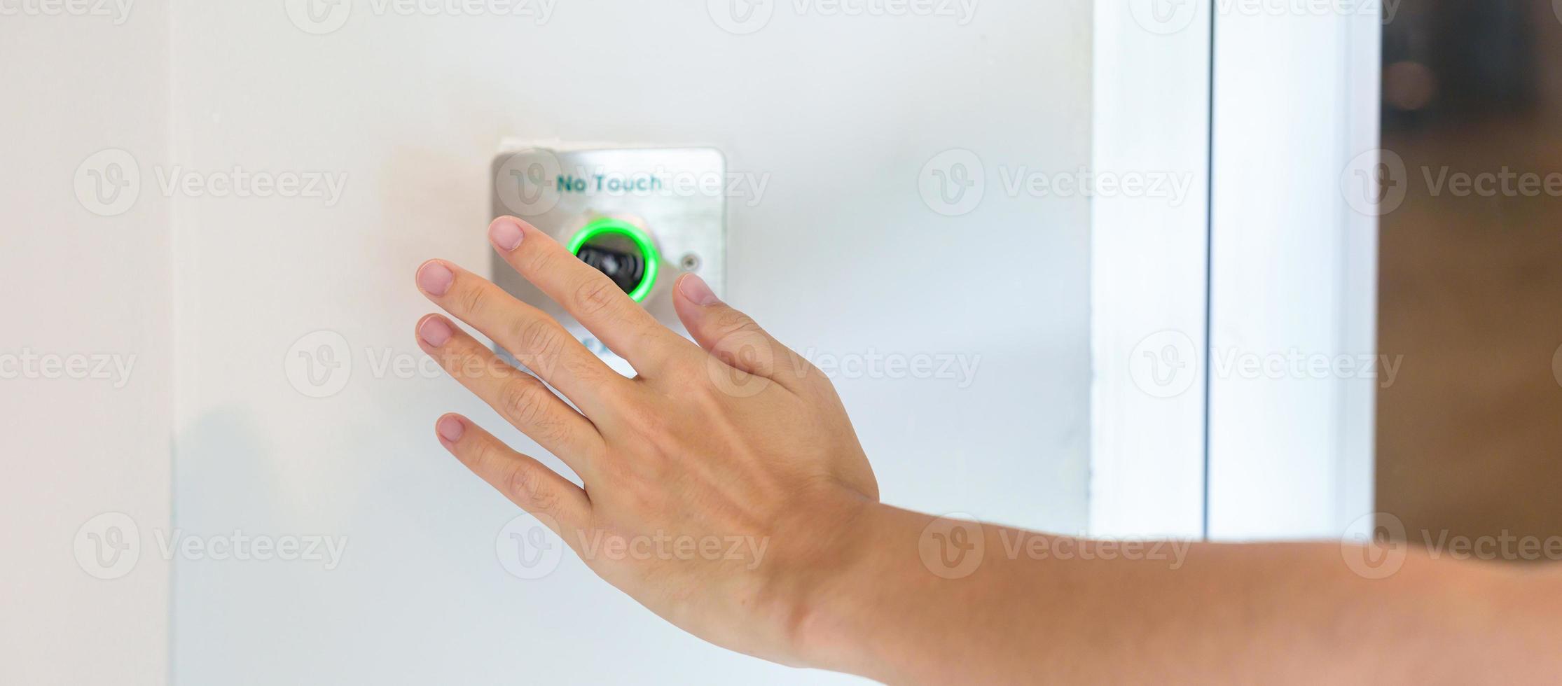 Hand open the door by No touch sensor switch on the wall at office or apartment. Contactless, modern, Technology and safety concept photo