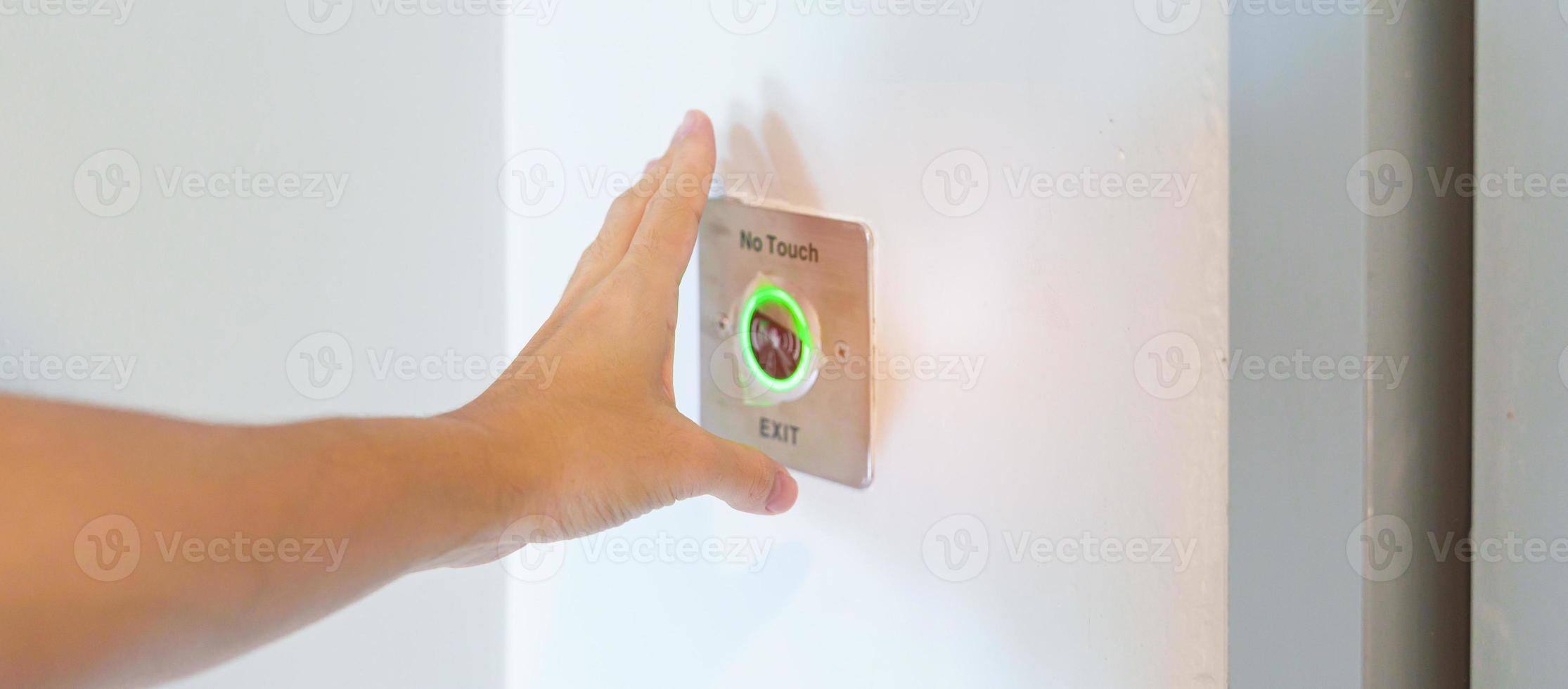 Hand open the door by No touch sensor switch on the wall at office or apartment. Contactless, modern, Technology and safety concept photo