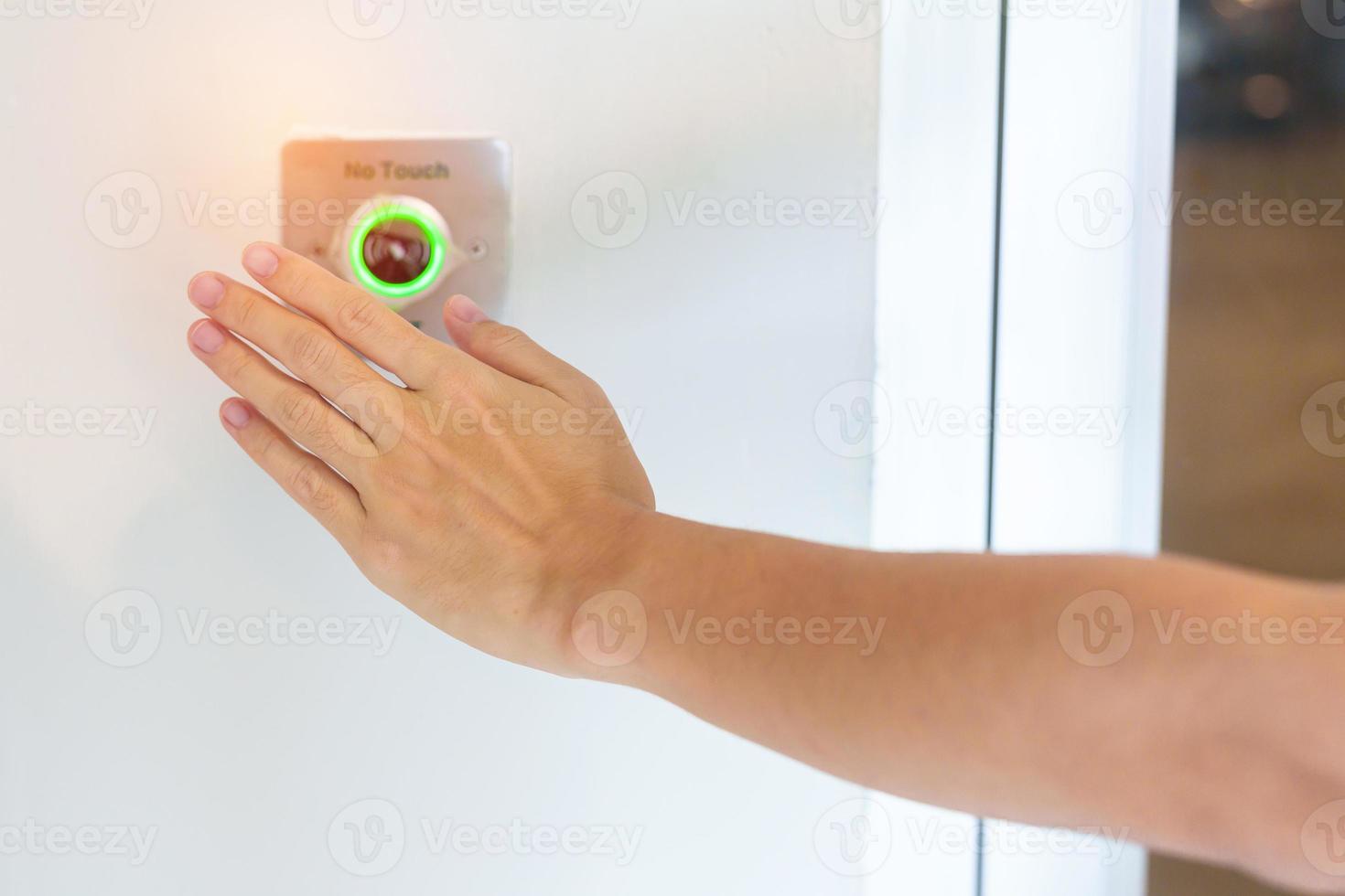Hand open the door by No touch sensor switch on the wall at office or apartment. Contactless, modern, Technology and safety concept photo