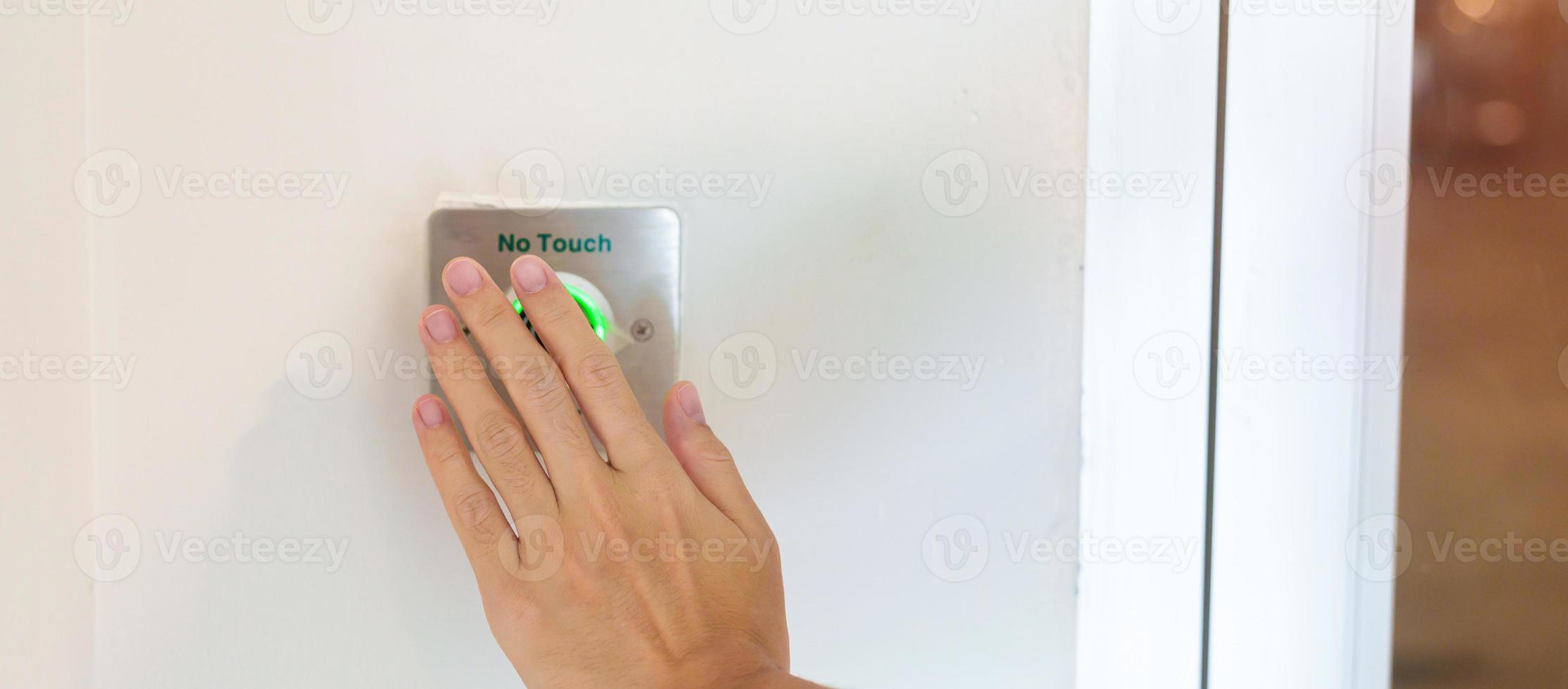 Hand open the door by No touch sensor switch on the wall at office or apartment. Contactless, modern, Technology and safety concept photo